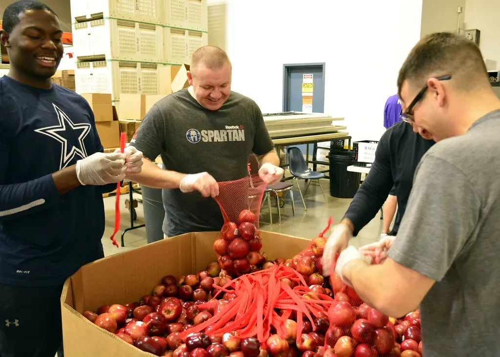 Des bénévoles trient une caisse de pommes dans l'entrepôt d'une banque alimentaire