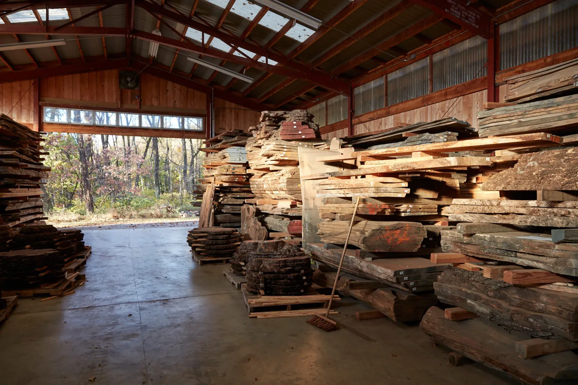 Des piles de planches de bois brut stockées sous un grand hangar ouvert
