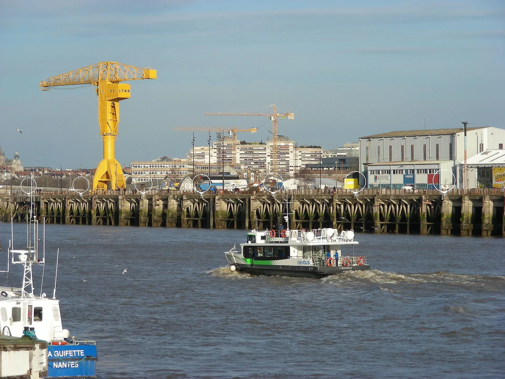 La grue jaune Titan sur l’île de Nantes, au bord de la Loire, avec une navette fluviale au premier plan