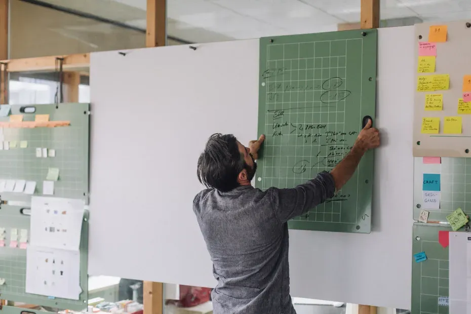 Un homme consulte un grand planning affiché au mur de son bureau